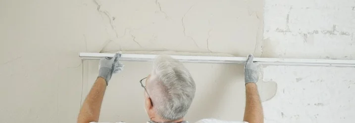 Person verputzt eine Wand mit Kartätsche.